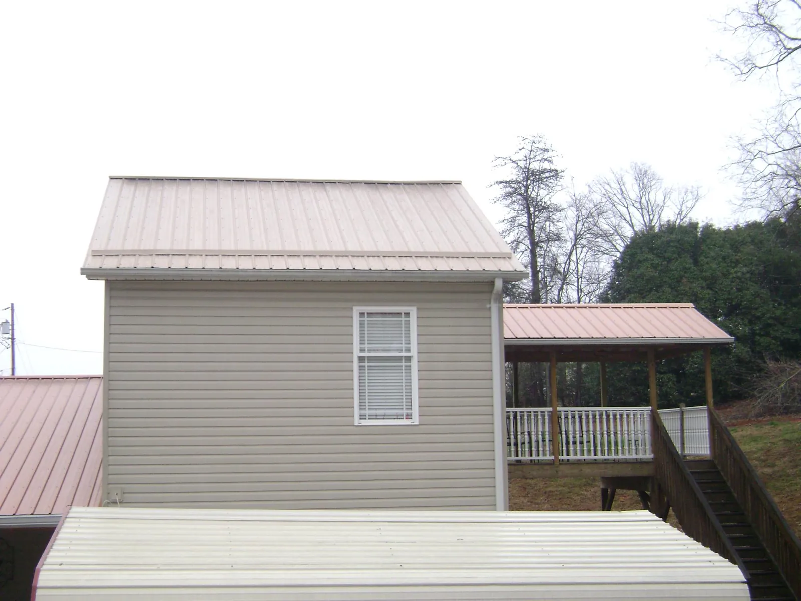 Tan metal roofs on a two story addition and attached porch, from a Roof Replacement job in New Ulm