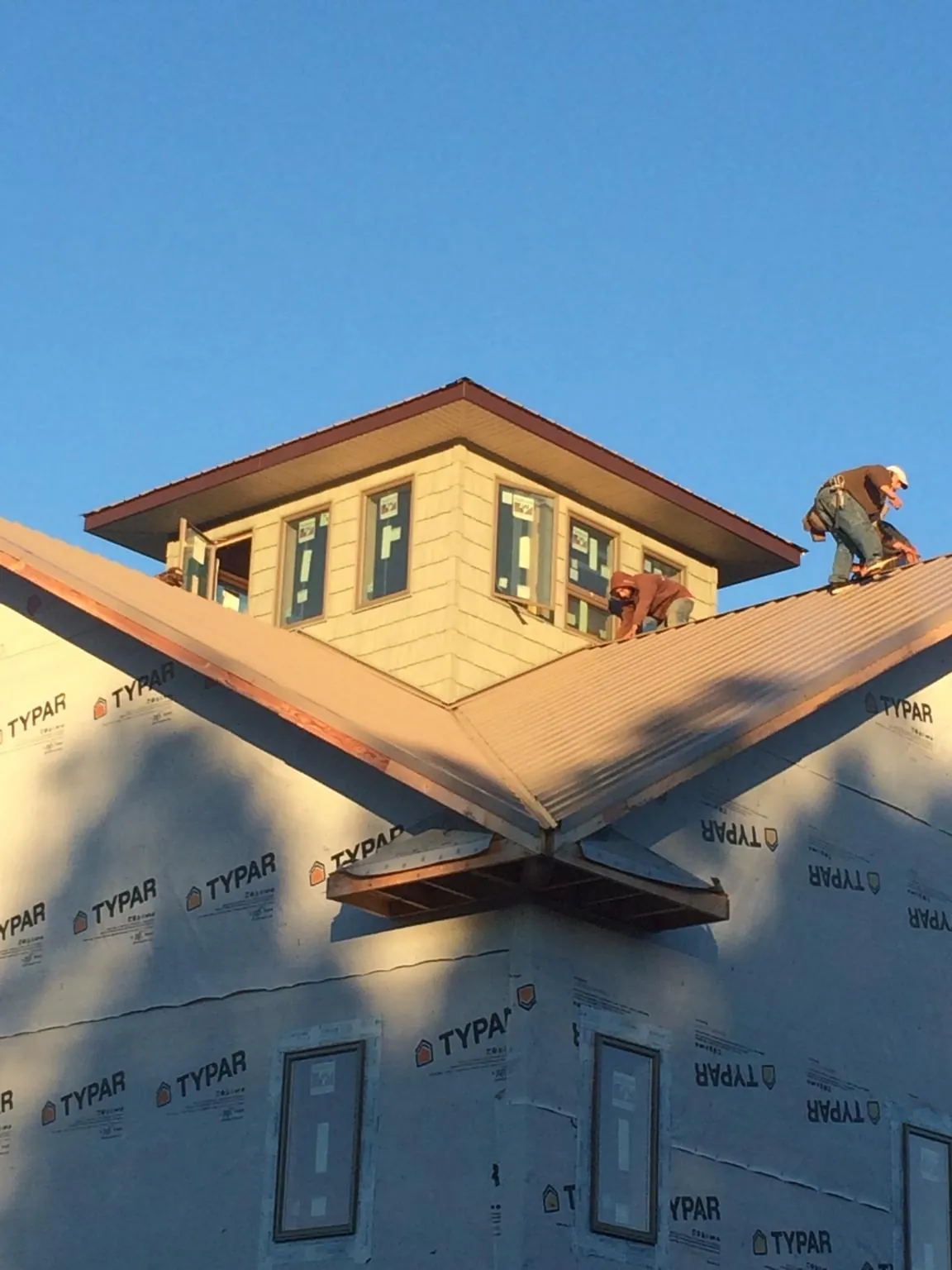 Roofers working around a rooftop cupola on a new metal roof at sunset — Roof Waterproofing in New Ulm by Roofing Brothers